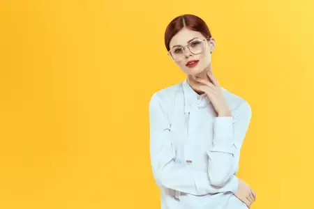 Элегантная красивая женщина в белой рубашке на желтом фоне