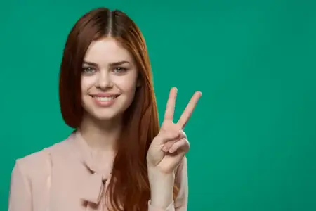 Симпатичная женщина показывает жест пальцем, привлекательно улыбаясь на изолированном фоне