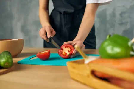 Домохозяйка на кухне нарезает овощи на разделочной доске
