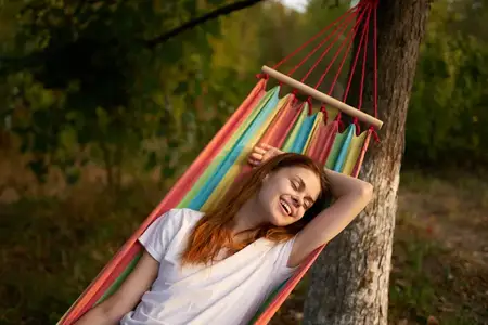 Женщина на открытом воздухе лежит в гамаке, отдыхая летом