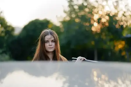 Красивая молодая женщина с длинными волосами держит палочки для еды, наслаждаясь здоровой едой на открытом воздухе на закате в окружении зелени, что отражает яркий образ жизни