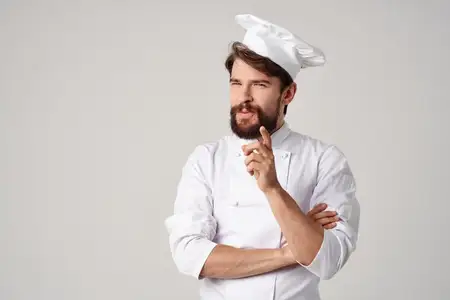 Бородатый мужчина в рабочей форме на кухне на светлом фоне