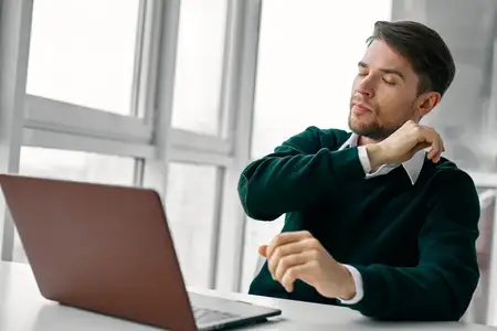 Мужчина сидит за своим столом с ноутбуком, работает с технологиями онлайн