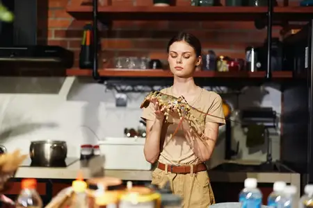 Женщина держит лобстера перед кухней, готовя свежее блюдо из морепродуктов на ужин