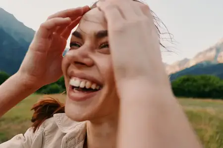 Портрет улыбающейся женщины на фоне активного отдыха на природе, выражающий счастье, наслаждение природой и жизнью на свежем воздухе