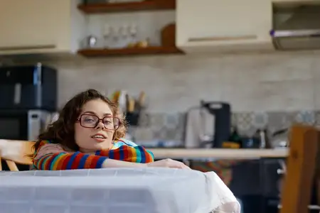 Непринужденная сцена женщины дома на кухне, расслабленная поза, мягкие естественные тона, интимное настроение, повседневная рутина, атмосфера заботы о себе, приглашающая и жизнерадостная атмосфера
