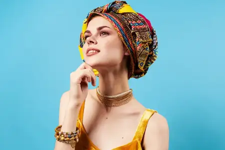 Весёлая женщина в разноцветной шали в африканском стиле на фоне синего фона