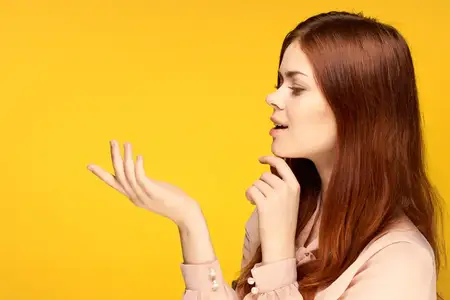 Симпатичная женщина жестикулирует руками на жёлтом фоне