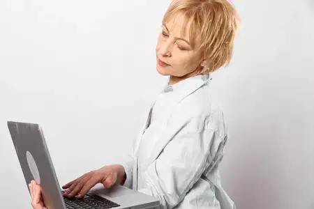 Женщина печатает на ноутбуке в офисе, вид сбоку