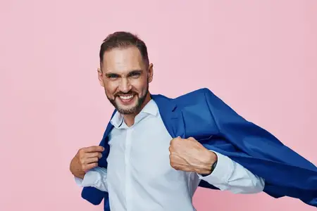 Изолированный цветной фон подчеркивает эмоции и лидерство: уверенный профессионал в синем пиджаке выражает решимость, целеустремленность и предпринимательский дух в чистой студийной обстановке