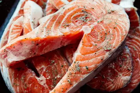 Маринованная красная рыба на тарелке, деревянный фон