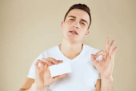 Мужчина с визитной карточкой в руках офис-менеджера на бежевом фоне