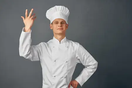 Мужчина в форме шеф-повара жестикулирует руками, выражая эмоции, в ресторане высокой кухни