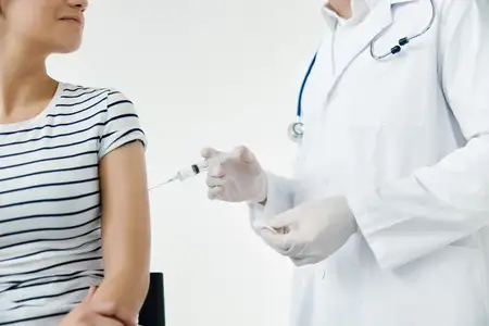 Врач в белом халате делает инъекцию в плечо женщине-пациентке