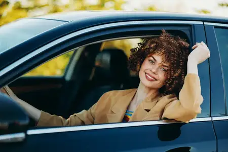 Весёлый водитель в припаркованном автомобиле, демонстрирующий лайфстайл-фотографию с винтажной цветовой палитрой и ностальгическим настроением, с акцентом на лёгкость и самовыражение