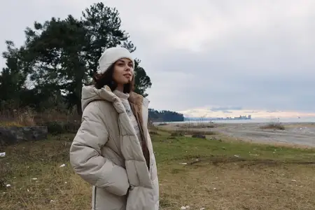 Уютная верхняя одежда на одинокой женщине у берега