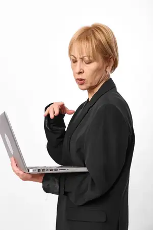 Изолирована на белом фоне, пожилая женщина с ноутбуком демонстрирует деловую работу, офисную рутину, черный блейзер, сосредоточенное выражение лица, руки на клавиатуре, профессиональный портрет…