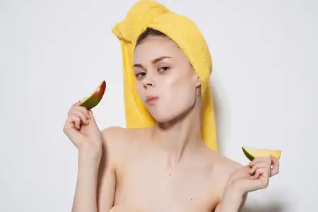 Женщина с обнажёнными плечами держит в руках манго