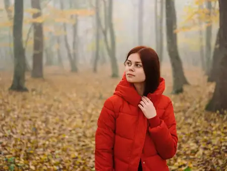 Женщина в красной куртке в лесу осенью