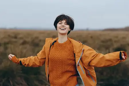 Женщина занимается пешим туризмом за городом: рюкзак, куртка, активный отдых