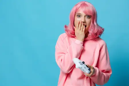 Красивая женщина с джойстиком в руках, играет, позирует на синем фоне