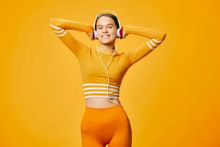 Спортсменка в подходящем оранжевом спортивном костюме в позе на ярком фоне; фитнес, тренировка, кардио, активный образ жизни и атмосфера тренажерного зала с жизнерадостным настроением