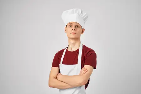 Мужчина в поварской форме держит в руках сковороду и готовит