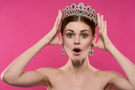 Портрет женщины с обнаженными плечами, украшениями и косметикой, позирующей на изолированном фоне