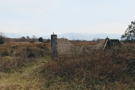 Пейзажный вид, сельское пастбище с горами, выветренные руины каменной стены, растительность и природа вдоль открытого поля, умиротворенный туристический пейзаж на открытом воздухе