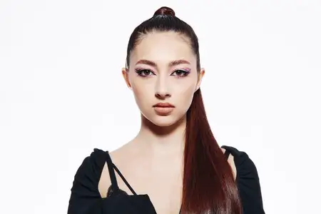 Крупный план модели с точной укладкой волос и яркой косметикой для глаз в трендовой одежде с открытыми плечами