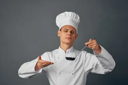 Повар-мужчина с половником в руках пробует блюда, ресторан, профессионал
