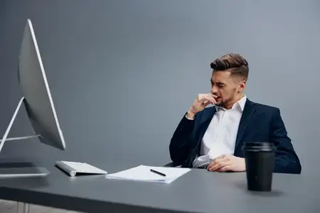 Уставшие бизнесмены с чашкой кофе работают за компьютером в офисе