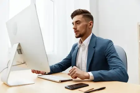 Красивый бизнесмен в очках работает за компьютером в офисе, используя современные технологии