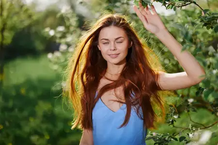 Портрет счастливой женщины, улыбающейся с зубами на солнце, с развевающимися длинными рыжими волосами