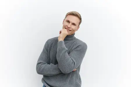 Счастливый мужчина с короткими волосами и тёплой улыбкой, одетый в фактурный серый свитер