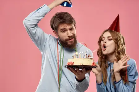 Мужчина и женщина на вечеринке с тортом на розовом фоне