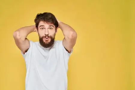 Бородатый мужчина в белой футболке на жёлтом фоне