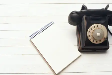 Ретро-телефон и блокнот на деревянном столе, вид сверху