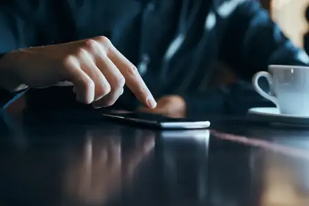 Бизнесмен с мобильным телефоном в кафе за столом, обрезанный вид