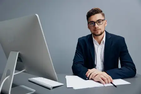 Красивый бизнесмен в очках работает за компьютером в офисе