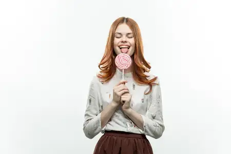 Весёлая женщина облизывает леденец, выражая радость и сладкие эмоции