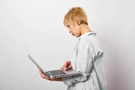 Женщина с ноутбуком в офисном освещении, напряженная и уставшая