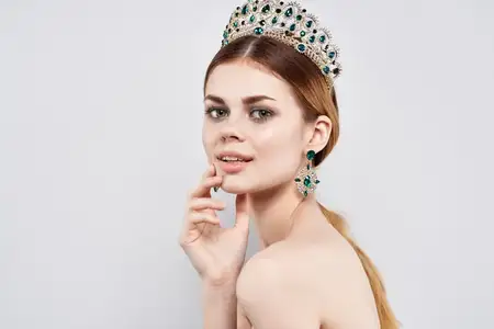 Красивая женщина с обнажёнными плечами, украшениями и косметикой, привлекательный взгляд на светлом фоне