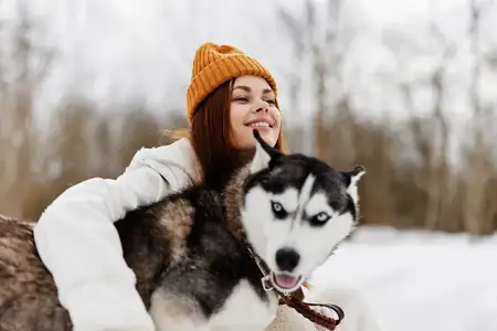 Женщина на улице в поле зимой гуляет с собакой, зимние каникулы