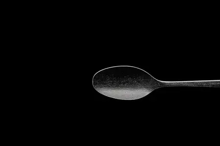 Искусно изготовленная серебряная ложка, изолированная на чёрном фоне, демонстрирующая её отражающую поверхность и плавные изгибы, идеально подходит для кулинарных концепций и концепций сервировки…