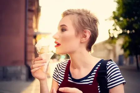 Женщина на отдыхе ест мороженое на улице летом