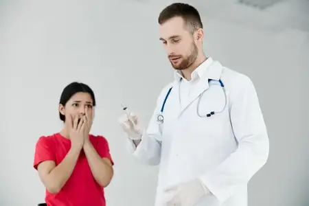 Пациентка закрывает лицо руками от страха перед уколами и вакцинацией