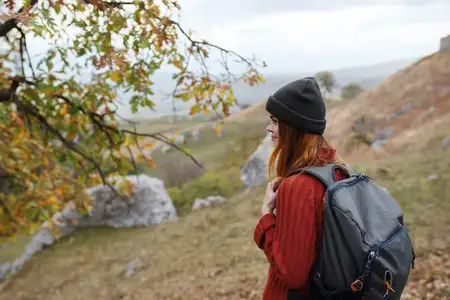 Женщина-туристка с рюкзаком в горах путешествует осенью