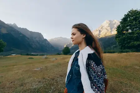 Женский портрет, горы, луг, пейзаж, природа, профиль, на открытом воздухе, вид сбоку на молодую женщину в повседневной куртке на травянистом поле, безмятежное настроение и солнечный свет на лице…