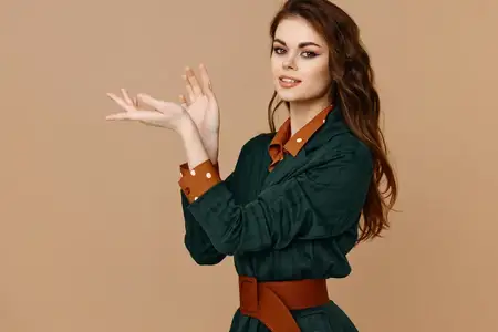 Модная женщина на бежевом фоне жестикулирует руками в модной одежде
